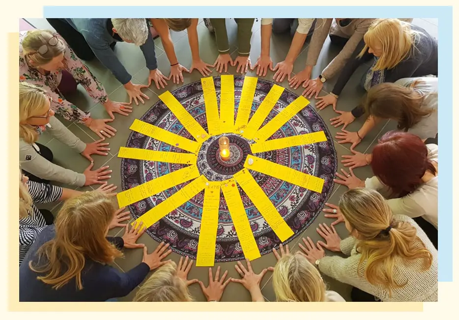Trainerinnen im Kreis um ein Mandala